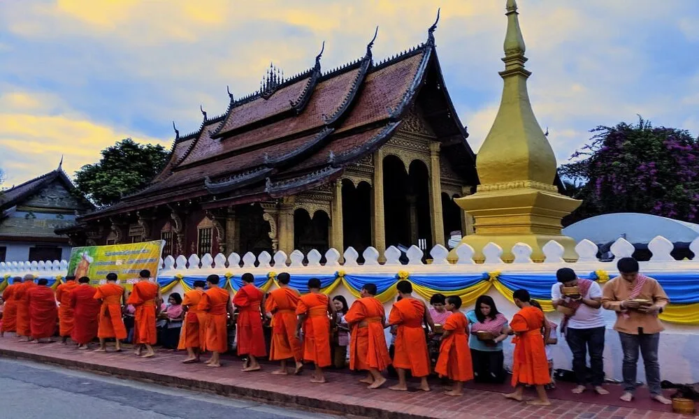 Monjes budistas en fila recibiendo ofrendas